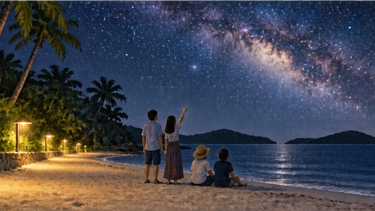 星空保護区に認定された離島の海岸で、遮光された街灯の下から満天の星空を見上げる人々
